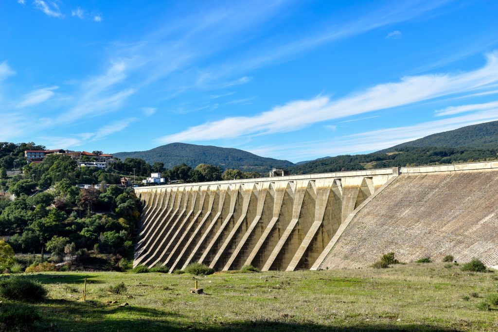 A scenic view of a large concrete dam surrounded by hills and greenery in Tunisia.